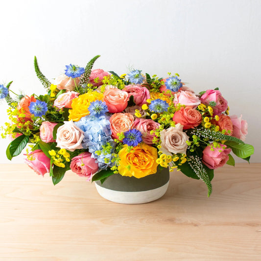 The Enchanted bouquet is a work of art full of summer themes and is a premium summer luxury setup. With beautiful unique roses,  Blue nigella and hydrangea accents, yellow Matricaria, white veronica, and alchemilla create this a summertime gem!