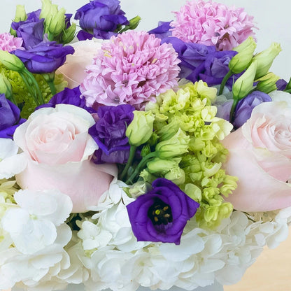 Purples, lavenders, and whites in a gentle, elegant blend. Purple lisianthus and hyacinth complement white hydrangea and light pink roses. Suitable for a variety of events!