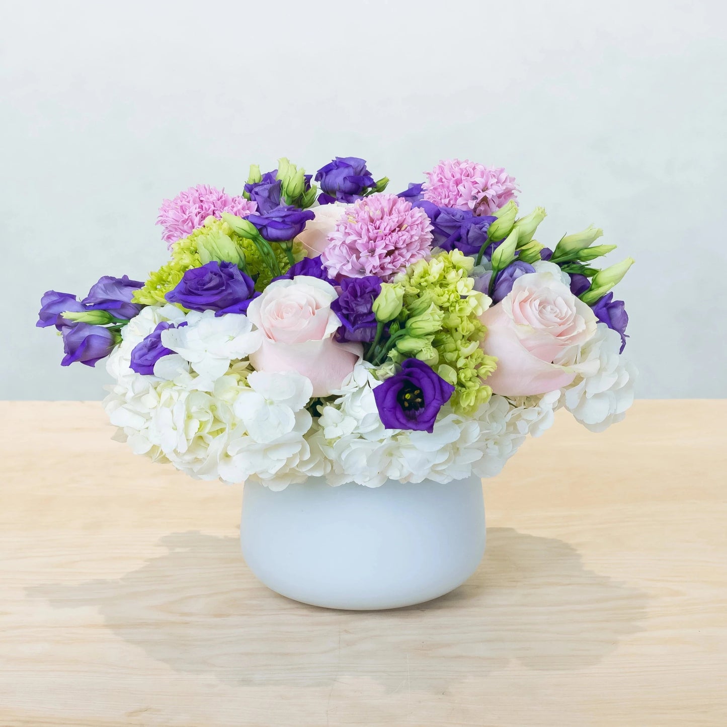 Purples, lavenders, and whites in a gentle, elegant blend. Purple lisianthus and hyacinth complement white hydrangea and light pink roses. Suitable for a variety of events!
