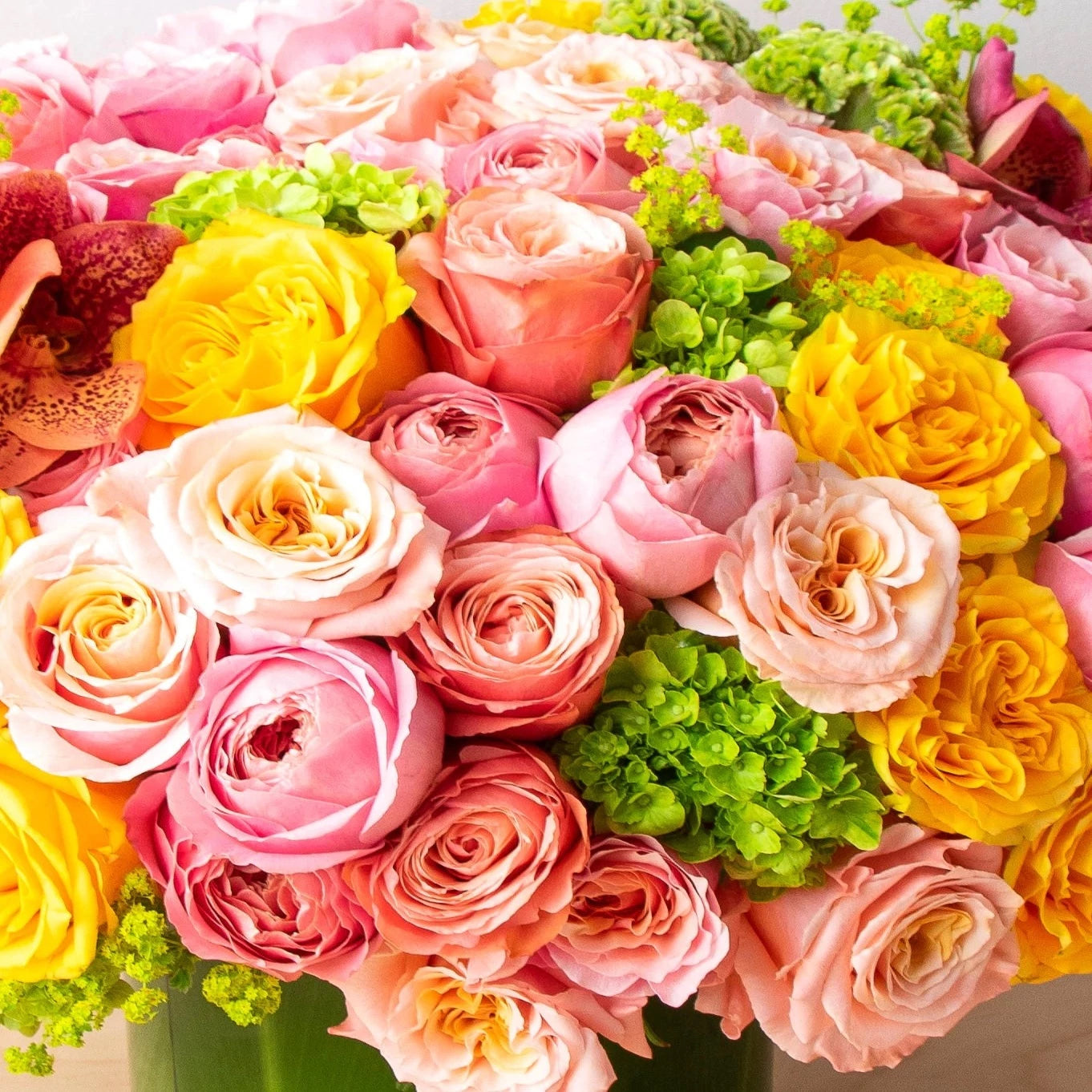 This beautiful bouquet is made up of unique garden roses that are artfully matched with orchids, hydrangeas, and other summer flowers.