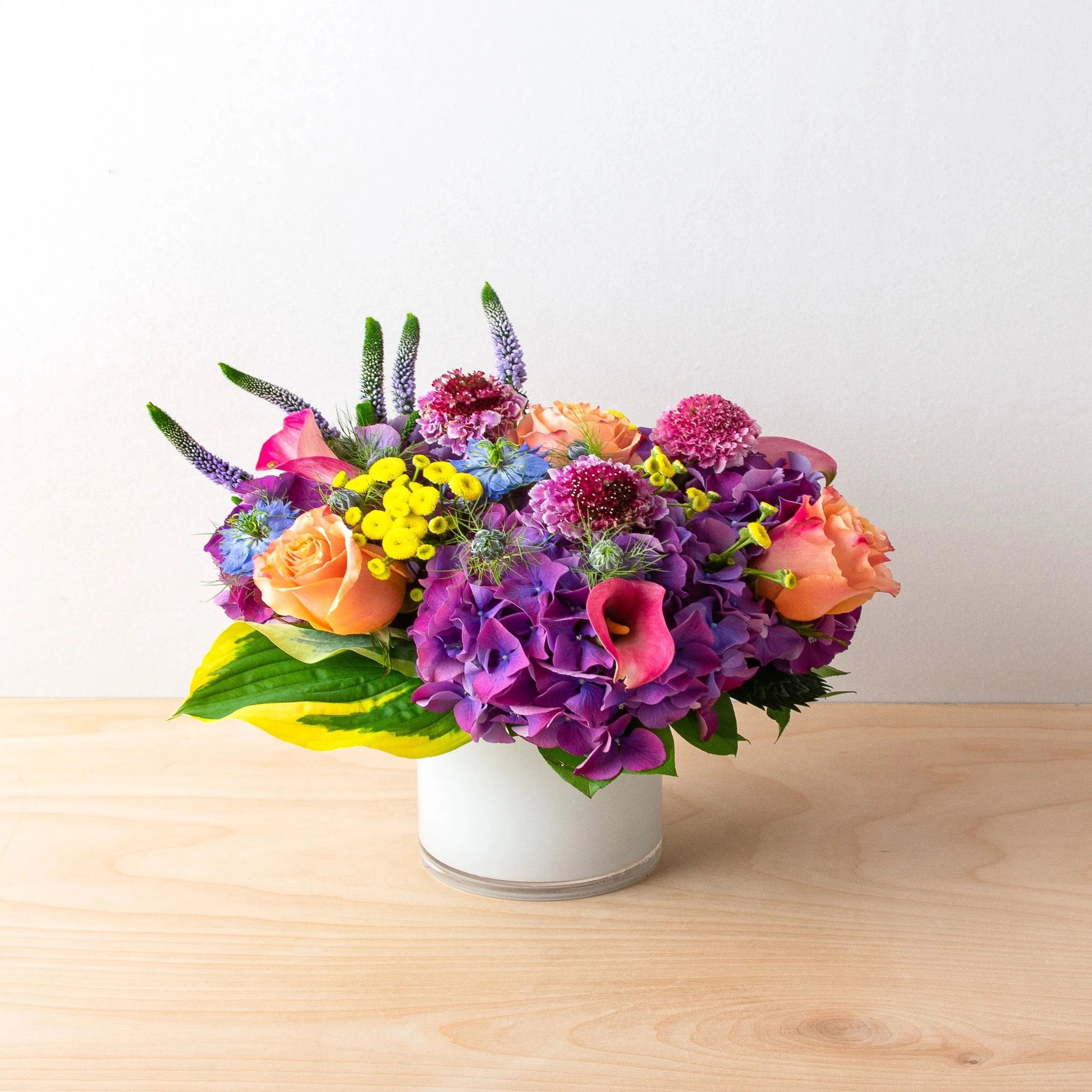 A classical mix of flowers that forms the perfect shade of enjoyment.   Flower List:  Purple Hydrangea  Peach Rose  Scabiosa  Veronica  Note: exact flowers will vary. Our team will always choose the freshest, most unique seasonal flower.