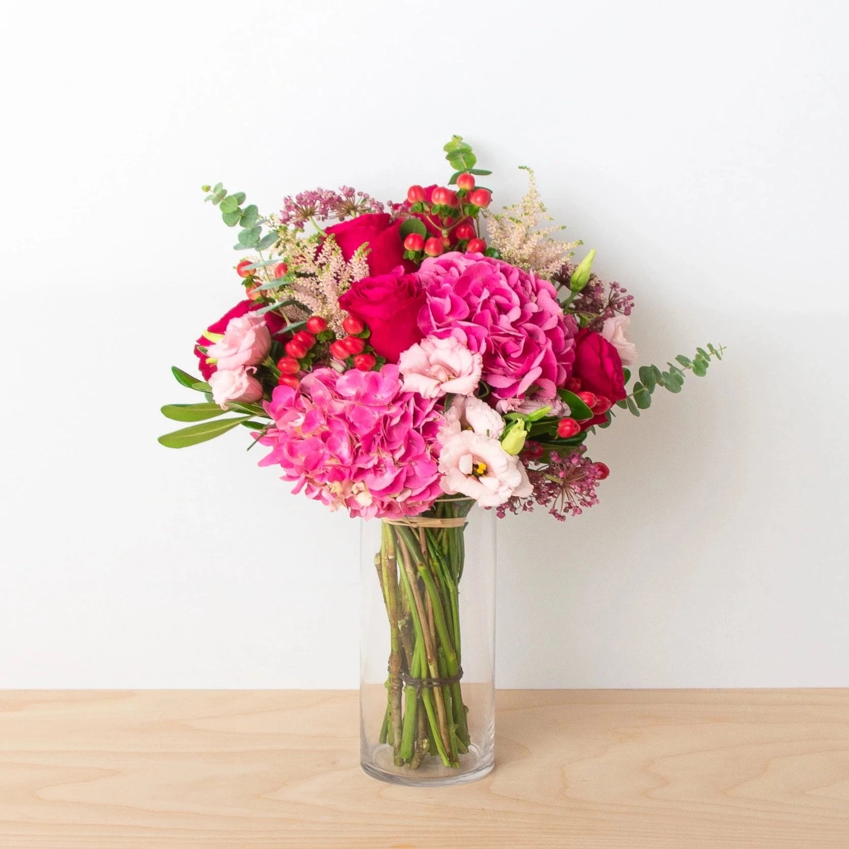 Vibrant reds and hot pinks are the perfect match-ups to show love.  Flower List:  Hot Pink Hydrangea  Lisianthus  Red Rose  Eucalyptus  Hypericum Berries  Note: exact flowers will vary. Our team will always choose the freshest, most unique seasonal flower.